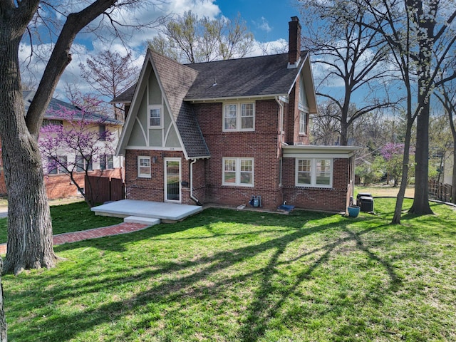 view of front facade with a chimney, cooling unit, brick siding, and a front yard
