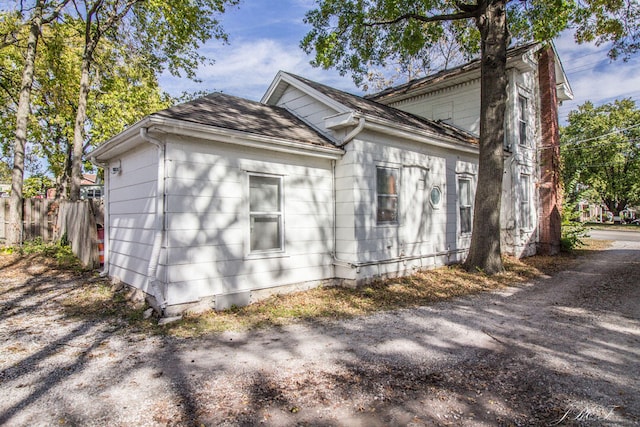 view of side of home featuring fence and roof with shingles