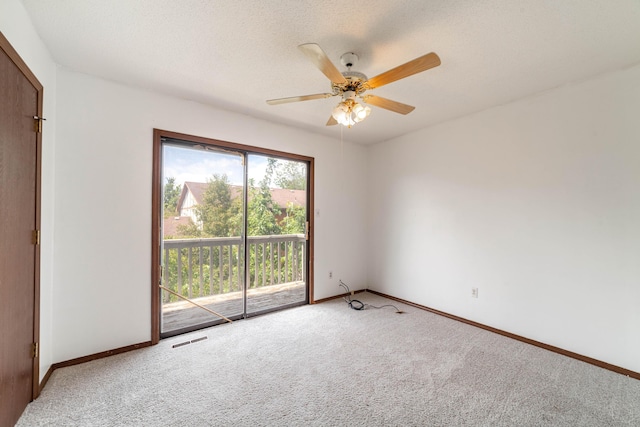 carpeted empty room featuring a textured ceiling, baseboards, ceiling fan, and visible vents