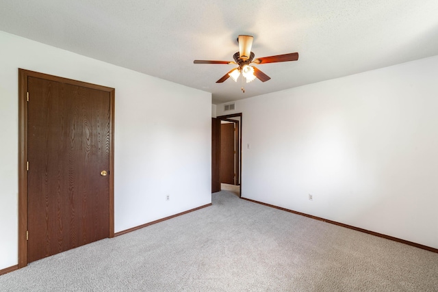 empty room with a ceiling fan, baseboards, light colored carpet, and visible vents
