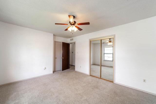 unfurnished bedroom featuring baseboards, a textured ceiling, visible vents, and light colored carpet