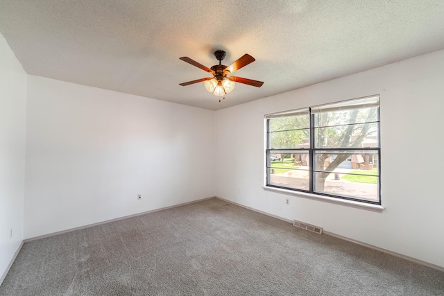 carpeted spare room featuring baseboards, a textured ceiling, visible vents, and a ceiling fan
