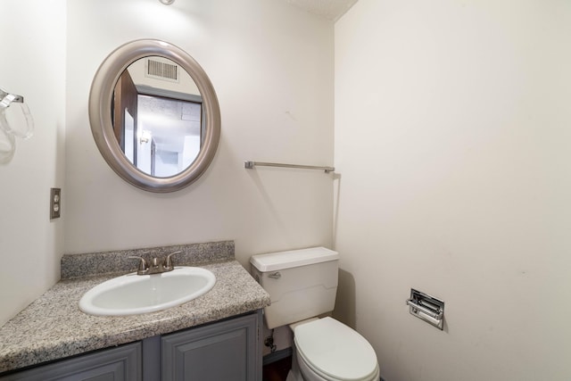 bathroom with toilet, vanity, and visible vents