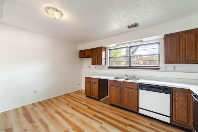 kitchen with light countertops, a sink, light wood-style floors, visible vents, and dishwasher