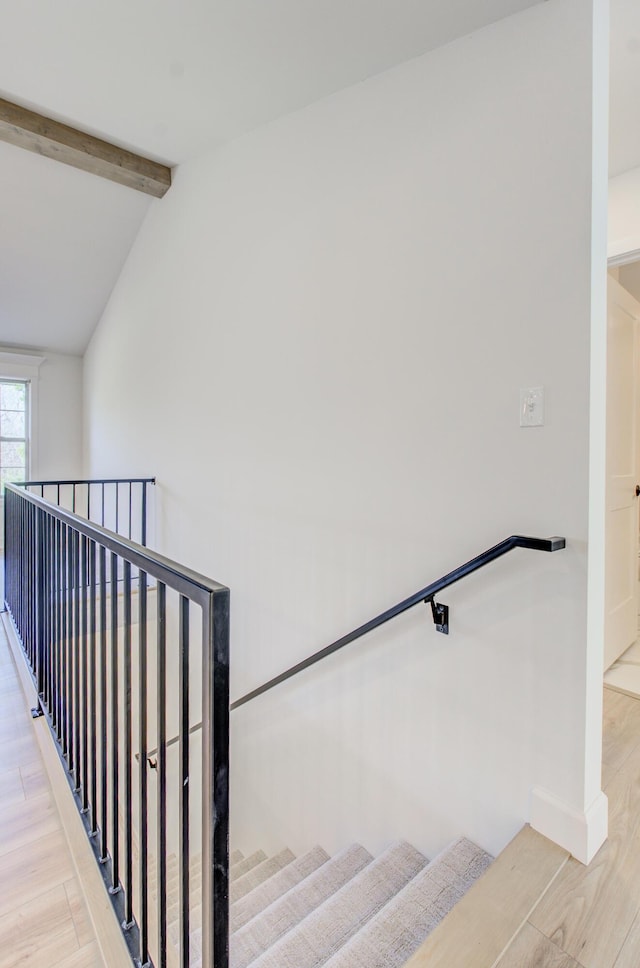 stairway with lofted ceiling with beams, baseboards, and wood finished floors