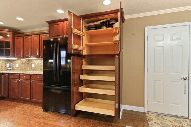 1204 S Walnut Ave, Salisbury, MO 65281 - kitchen featuring light stone counters, backsplash, freestanding refrigerator, crown molding, and wood finished floors