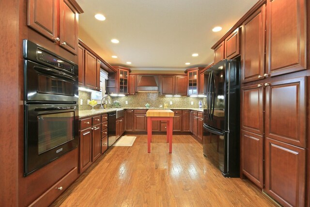 1204 S Walnut Ave, Salisbury, MO 65281 - kitchen featuring custom exhaust hood, glass insert cabinets, tasteful backsplash, black appliances, and light wood finished floors
