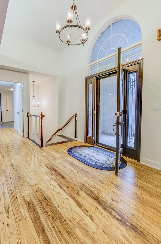 foyer entrance featuring a chandelier, a wealth of natural light, hardwood / wood-style flooring, and baseboards