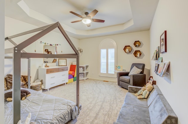 bedroom featuring a tray ceiling, ceiling fan, light colored carpet, and baseboards