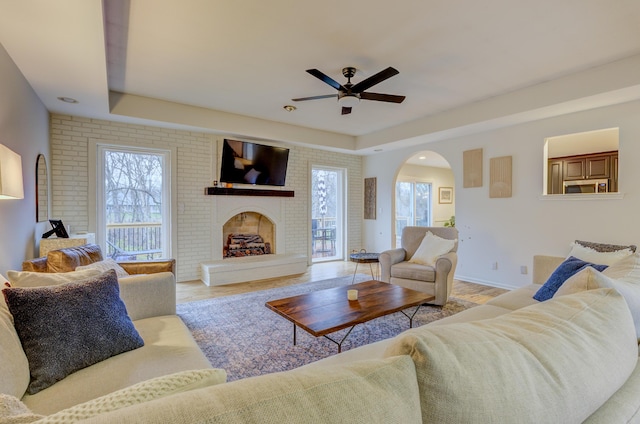living room with arched walkways, a healthy amount of sunlight, ceiling fan, and wood finished floors