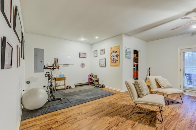 sitting room featuring wood finished floors, ceiling fan, baseboards, and electric panel
