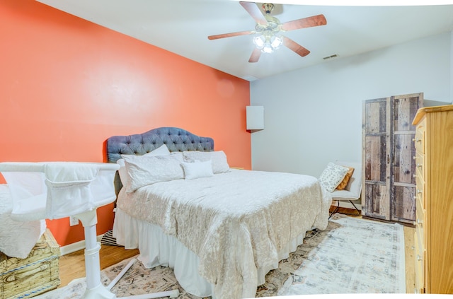 bedroom with wood finished floors, a ceiling fan, and visible vents