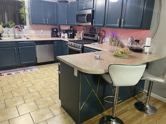 4011 Spring Cress Dr, Columbia, MO 65202 - kitchen featuring stainless steel appliances, blue cabinetry, a sink, light countertops, and a peninsula