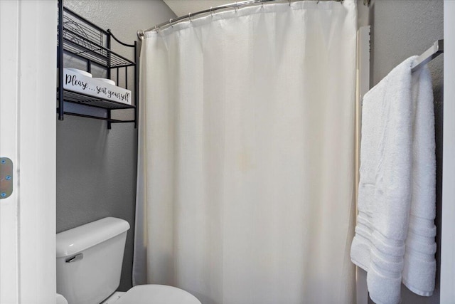full bathroom featuring toilet and a textured wall