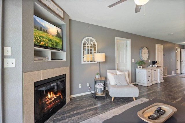 living room featuring a ceiling fan, baseboards, visible vents, wood finished floors, and a fireplace