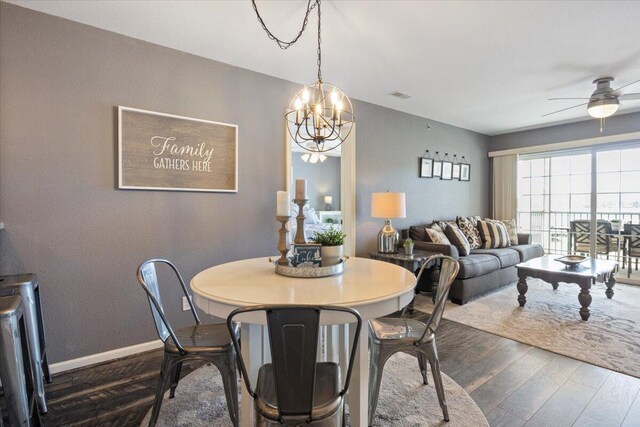 dining space featuring baseboards, dark wood finished floors, visible vents, and ceiling fan with notable chandelier