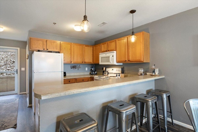 kitchen featuring a peninsula, white appliances, dark wood finished floors, light countertops, and baseboards