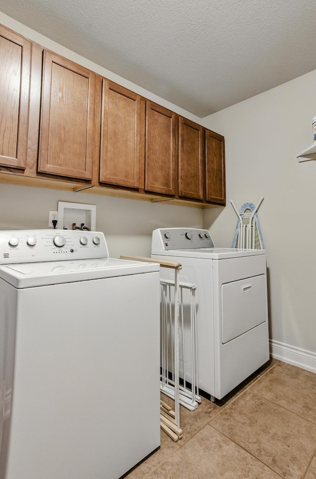 laundry area featuring independent washer and dryer, light tile patterned floors, and cabinet space