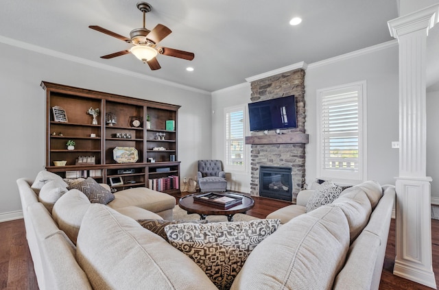 living room featuring ornate columns, ceiling fan, dark wood finished floors, and a stone fireplace