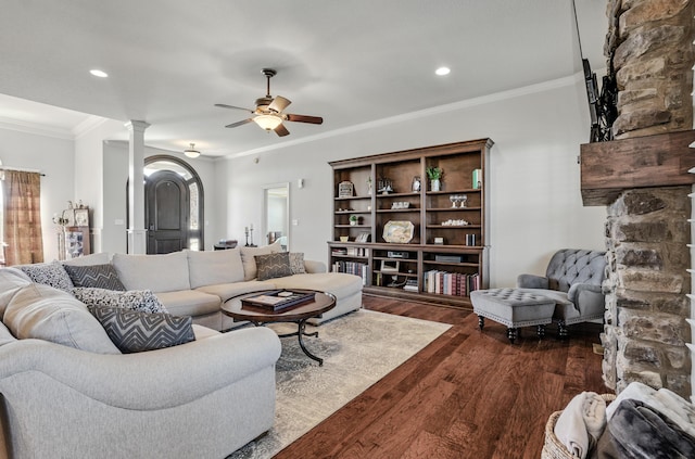 living area featuring dark wood-style flooring, ornate columns, a ceiling fan, and crown molding