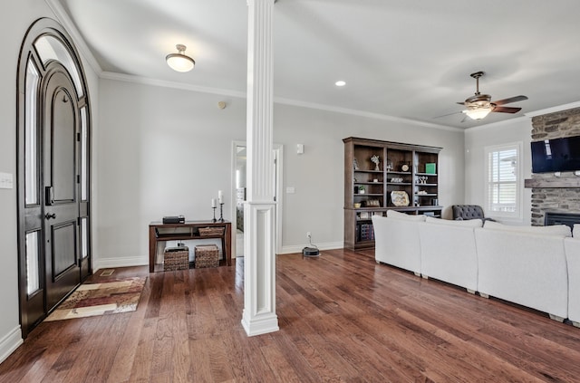 living area with ornate columns, dark wood finished floors, ornamental molding, and a ceiling fan