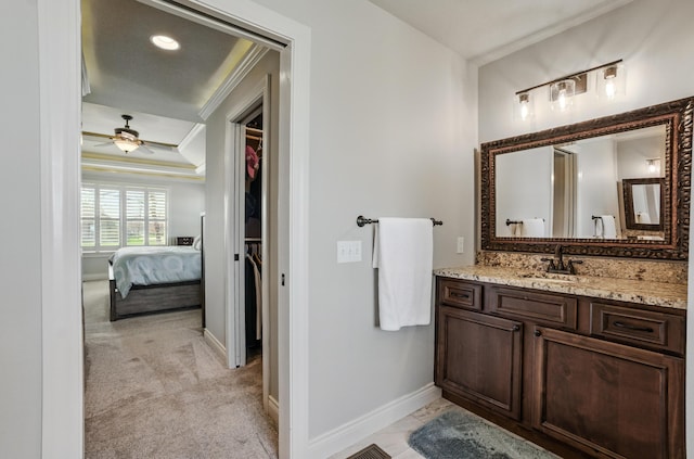 bathroom featuring vanity, baseboards, a spacious closet, crown molding, and a ceiling fan