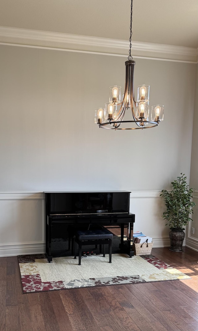sitting room featuring baseboards, a notable chandelier, wood finished floors, and crown molding