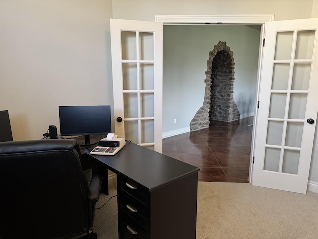home office with dark colored carpet and baseboards