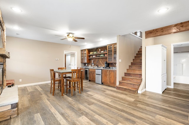 dining room with indoor wet bar, light wood-type flooring, stairway, a ceiling fan, and wine cooler