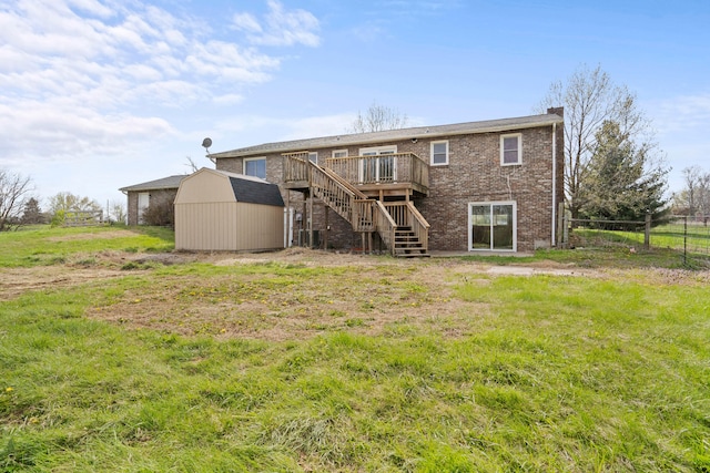 back of property with stairs, a shed, a wooden deck, an outbuilding, and brick siding