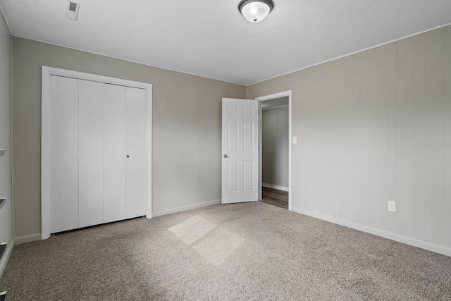 unfurnished bedroom with baseboards, carpet floors, and a closet
