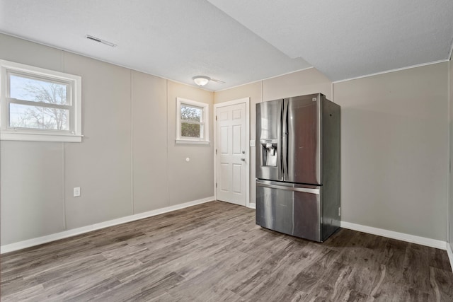 kitchen with stainless steel refrigerator with ice dispenser, wood finished floors, visible vents, and baseboards