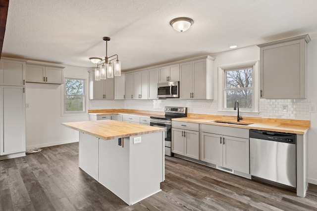 kitchen with wood counters, a sink, backsplash, and appliances with stainless steel finishes