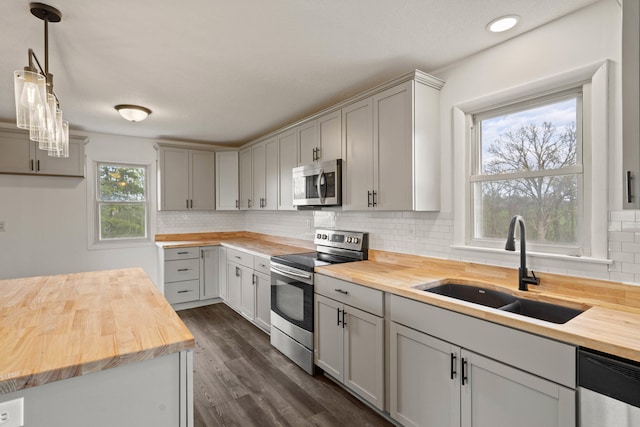 kitchen featuring backsplash, appliances with stainless steel finishes, wooden counters, and a sink