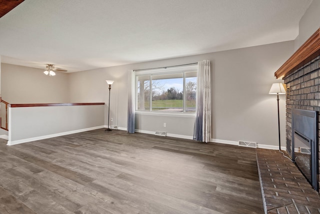unfurnished living room featuring baseboards, visible vents, a ceiling fan, wood finished floors, and a fireplace