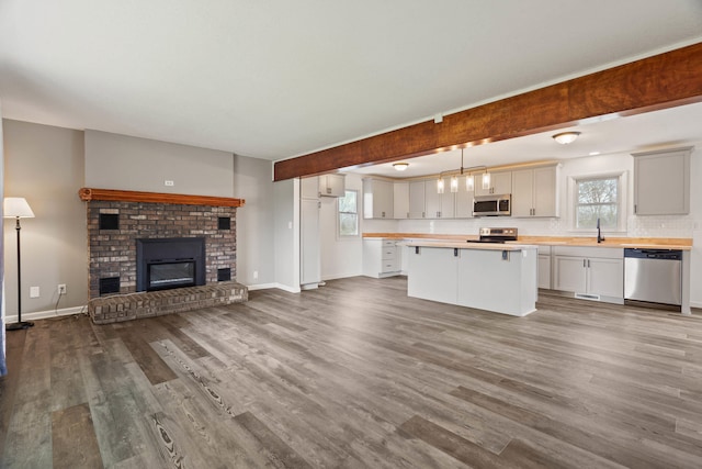 unfurnished living room featuring a healthy amount of sunlight, wood finished floors, and a sink
