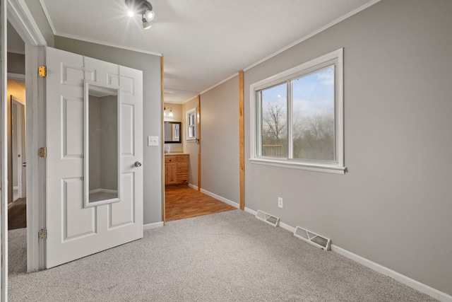 unfurnished bedroom with visible vents, carpet floors, and ornamental molding