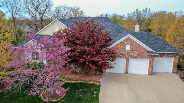 view of front of property featuring driveway, brick siding, a shingled roof, and a garage