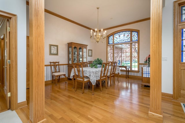 dining room with ornamental molding, light wood finished floors, a chandelier, a high ceiling, and baseboards