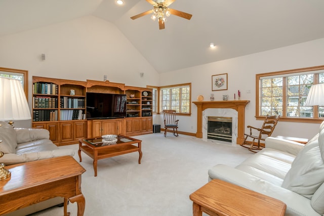 living room featuring baseboards, ceiling fan, high vaulted ceiling, a fireplace, and light colored carpet