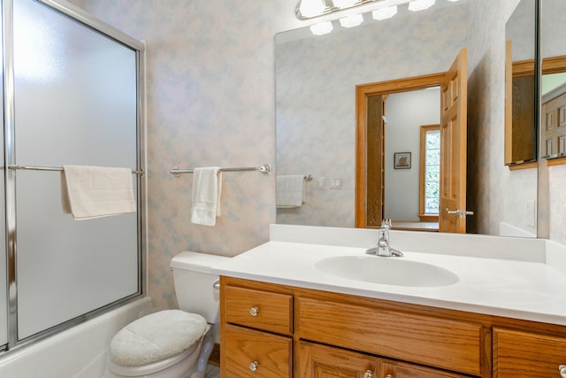 bathroom featuring vanity, toilet, wallpapered walls, and enclosed tub / shower combo