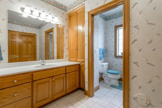 bathroom featuring toilet, tile patterned floors, vanity, and wallpapered walls