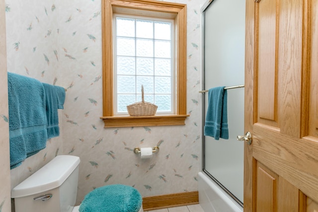 bathroom with toilet, baseboards, tile patterned floors, and bath / shower combo with glass door