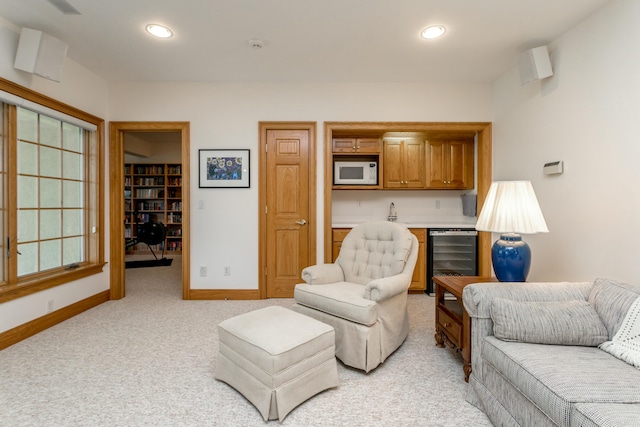 living room featuring light colored carpet, recessed lighting, beverage cooler, baseboards, and bar area