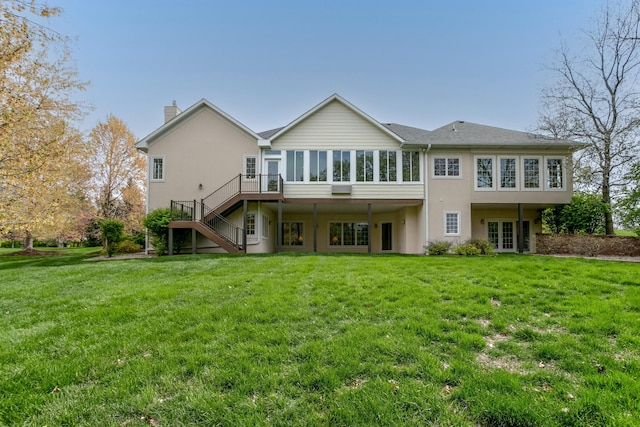 rear view of house with a chimney, a yard, stairway, and a sunroom