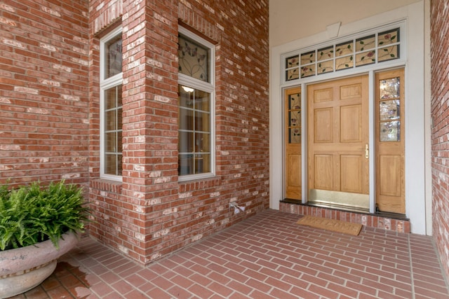 doorway to property featuring a porch and brick siding