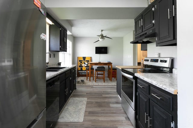 kitchen featuring a ceiling fan, a sink, under cabinet range hood, stainless steel appliances, and dark cabinets