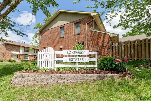 community / neighborhood sign with a yard and fence