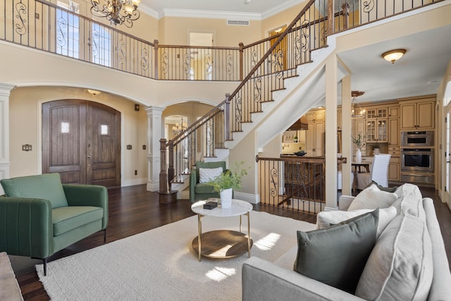3207 Rivington Dr, Columbia, MO 65203 - living area with arched walkways, a chandelier, decorative columns, stairs, and wood finished floors