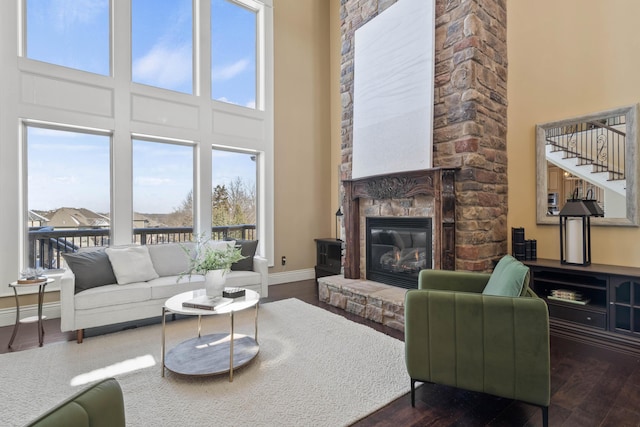 3207 Rivington Dr, Columbia, MO 65203 - living room featuring a high ceiling, dark wood-type flooring, a stone fireplace, baseboards, and stairway